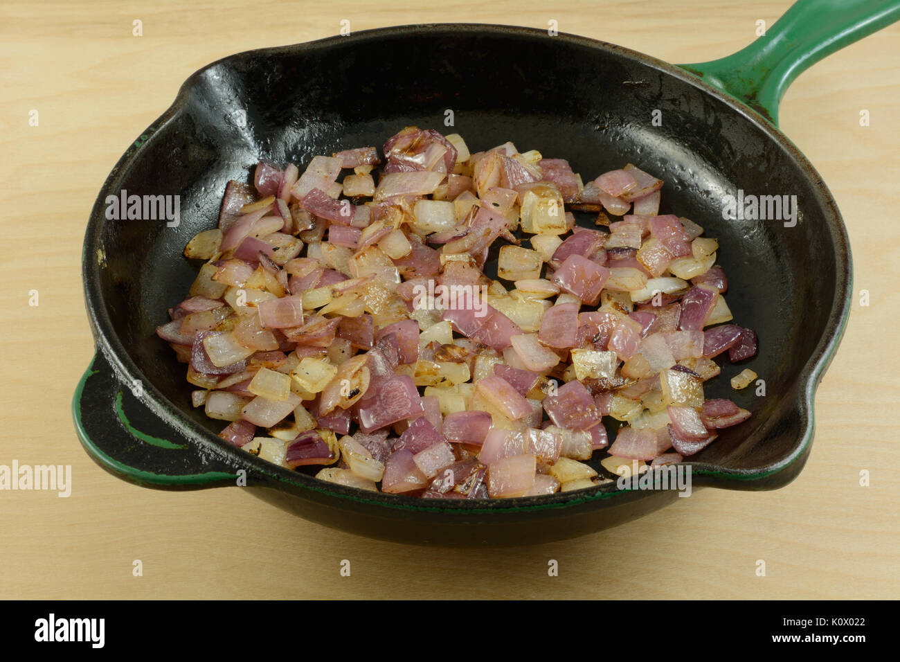 Sauteed chopped red onions in cast iron frying pan skillet Stock Photo