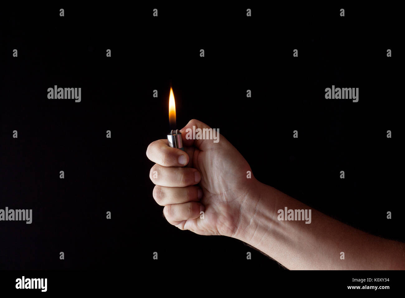 hand holding a lighter in a dark atmosphere Stock Photo