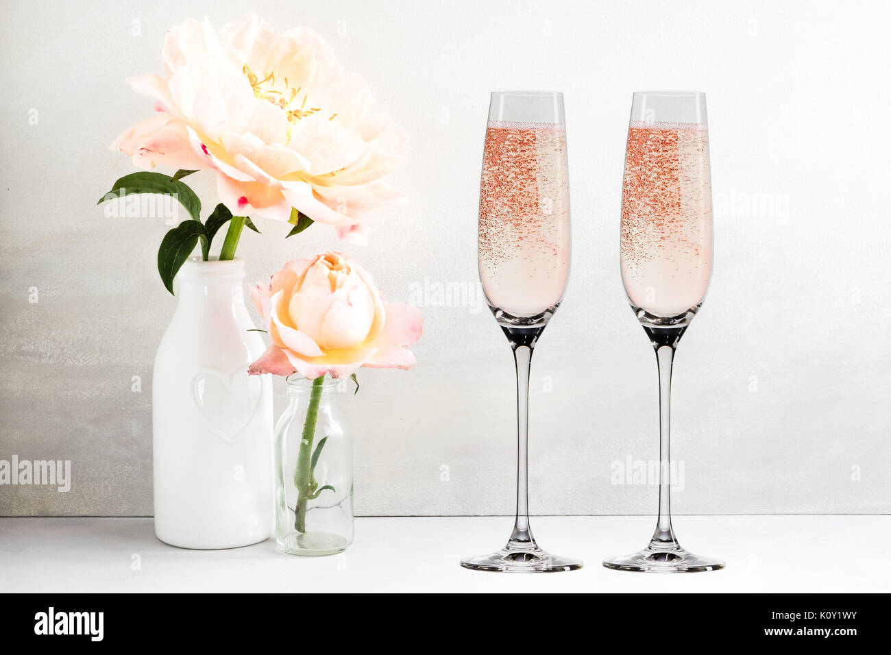 Floral mock-up of 2 champagne glasses next to a vase of flowers, perfect for businesses who sell decals, vinyl stickers, just overlay your design Stock Photo