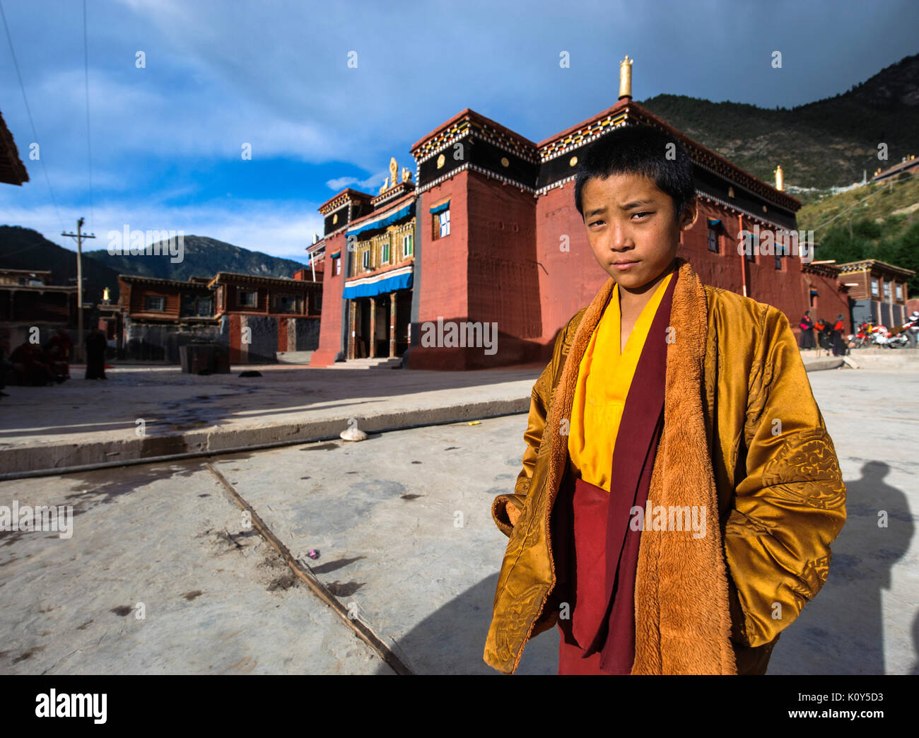 A young Tibetan buddhist monk by his monastery Stock Photo