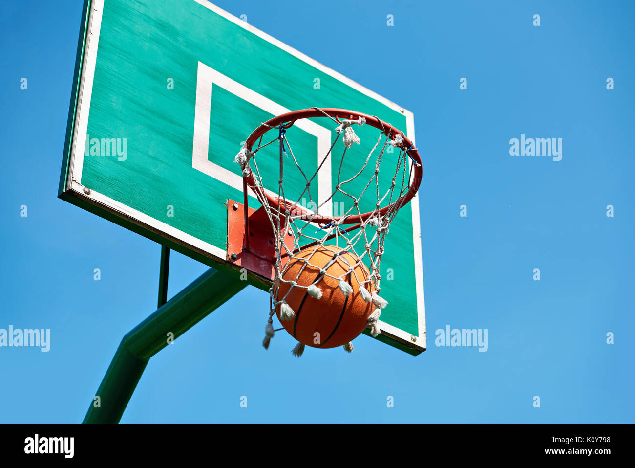 Basketball basket on a street sport ground and an orange ball on a blue sky background Stock Photo