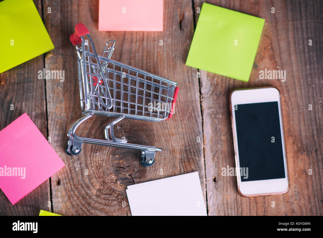 Shopping Cart, mobile phone and paper notes on wooden background Stock ...