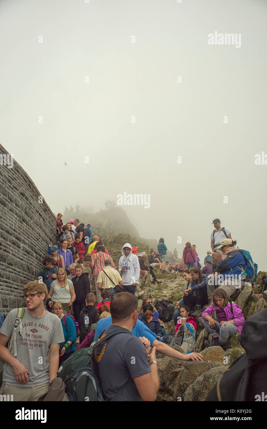 Crowds of hikers resting and taking in the view from the summit of Mount Snowdon in Wales, UK Stock Photo