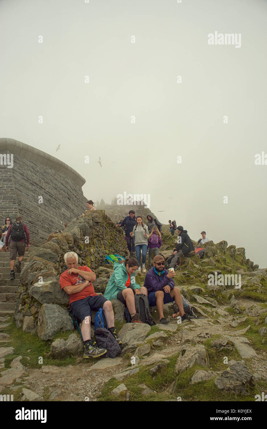 Crowds of walkers resting and taking in the view from the summit of Mount Snowdon Stock Photo