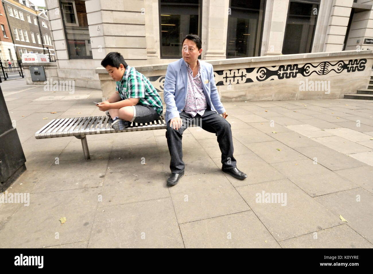 London England, UK. Asian man and his son using a mobile phone Stock Photo