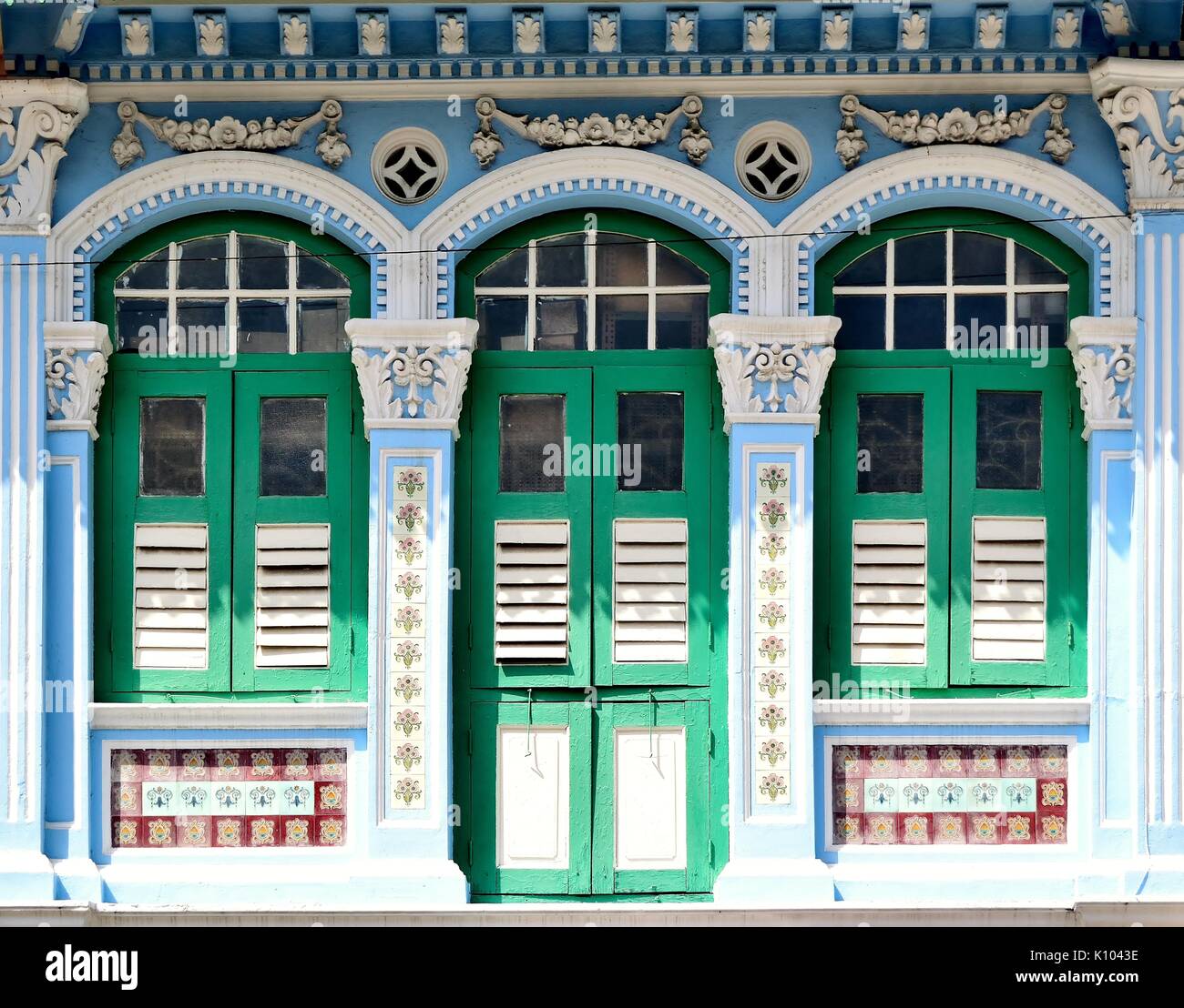 Traditional shop house exterior with green wooden louvered shutters,  arched windows ornate carvings in the Little India District of Singapore Stock Photo