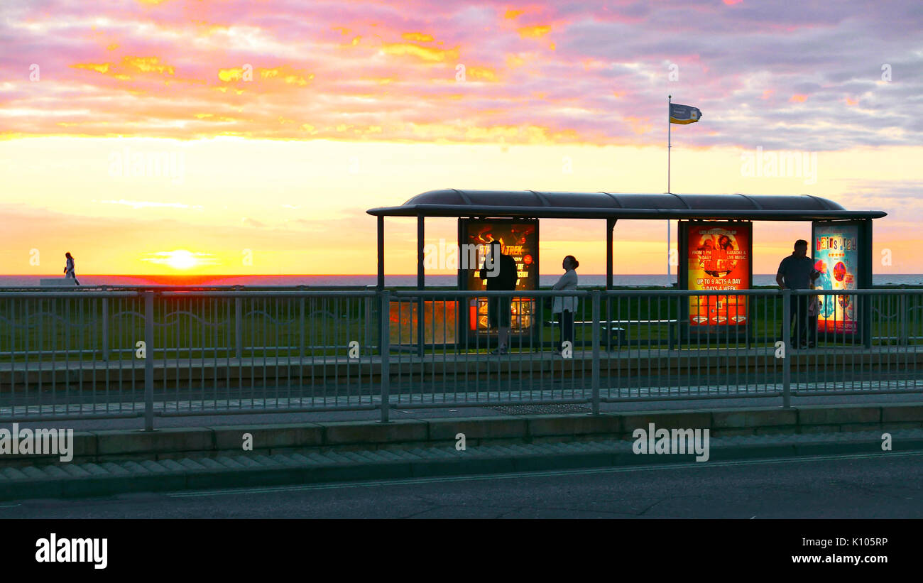 People waiting for a tram at shelter on Blackpool Promenade at sunset Stock Photo