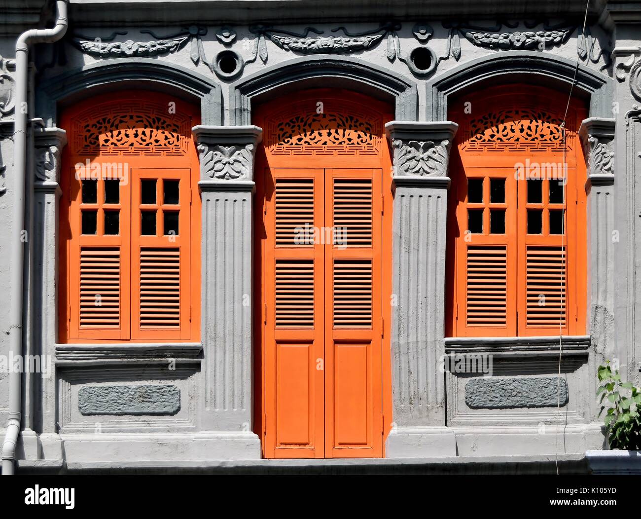 Traditional shop house exterior with orange wooden louvered shutters,  windows and ornate ventilation ducts in the Little India District of Singapore Stock Photo