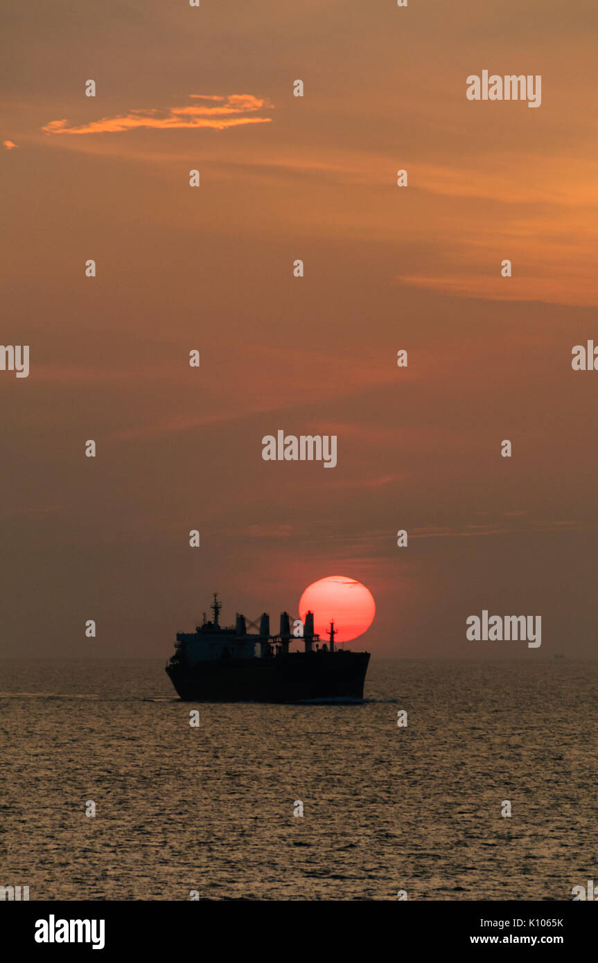 Cargo Ship at Sunset Approaching Singapore Strait Stock Photo