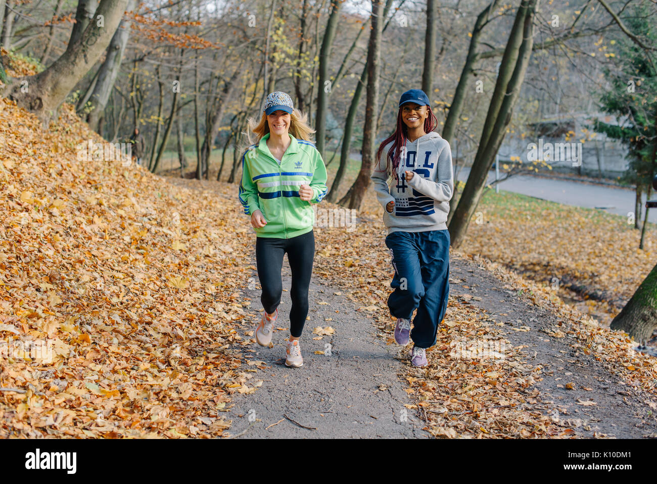 Two sportswomen running in park. Blonde and african girls. Golden autamn Stock Photo