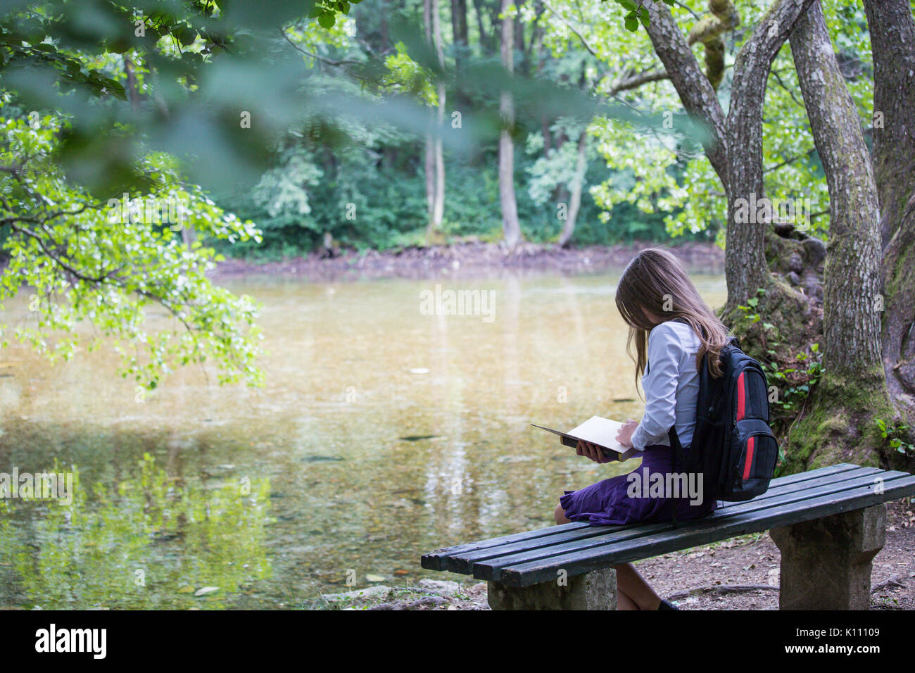 Pretty Little Blonde Schoolgirl With Backpack Sitting On The Bench