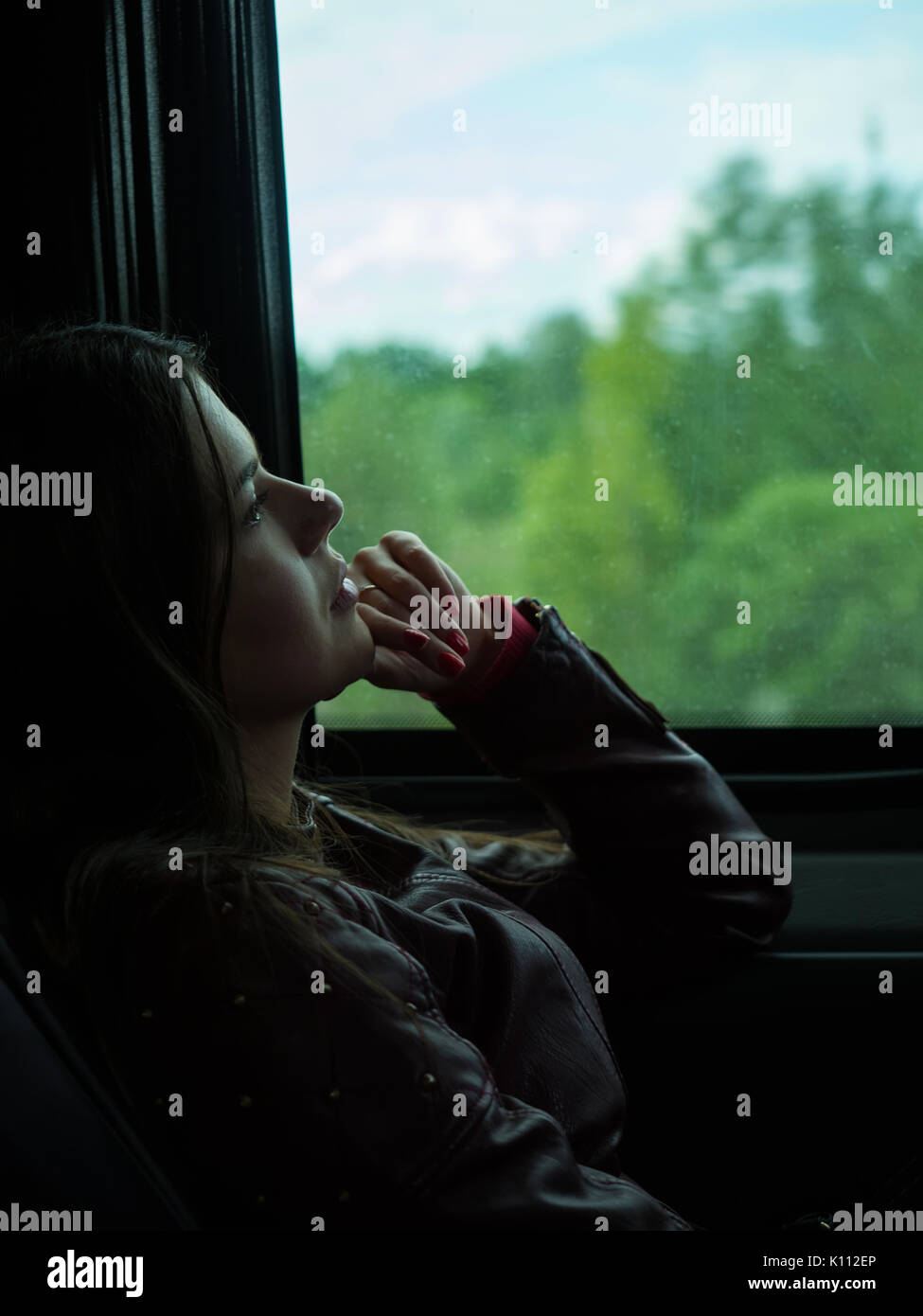 Sad girl looks out the window of a car on rainy day Stock Photo ...