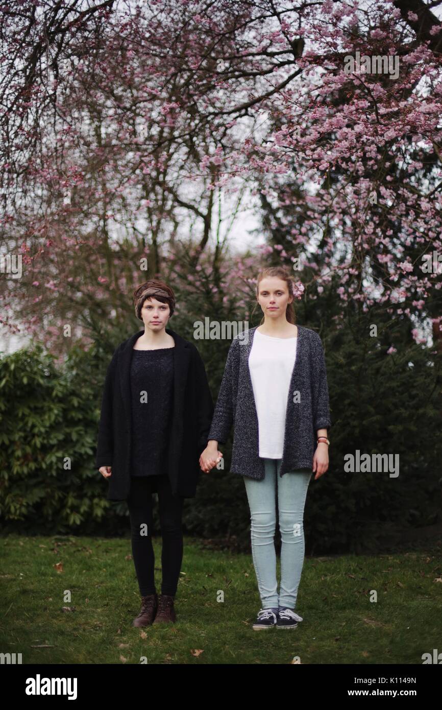Two young women holding hands in a park Stock Photo