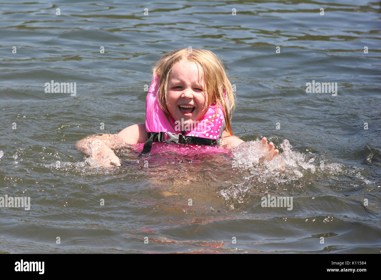 GIRL (6) WEARING LIFE JACKET AND SWIMMING IN LAKE SACRAMENTO COUNTY, CALIFORNIA Stock Photo