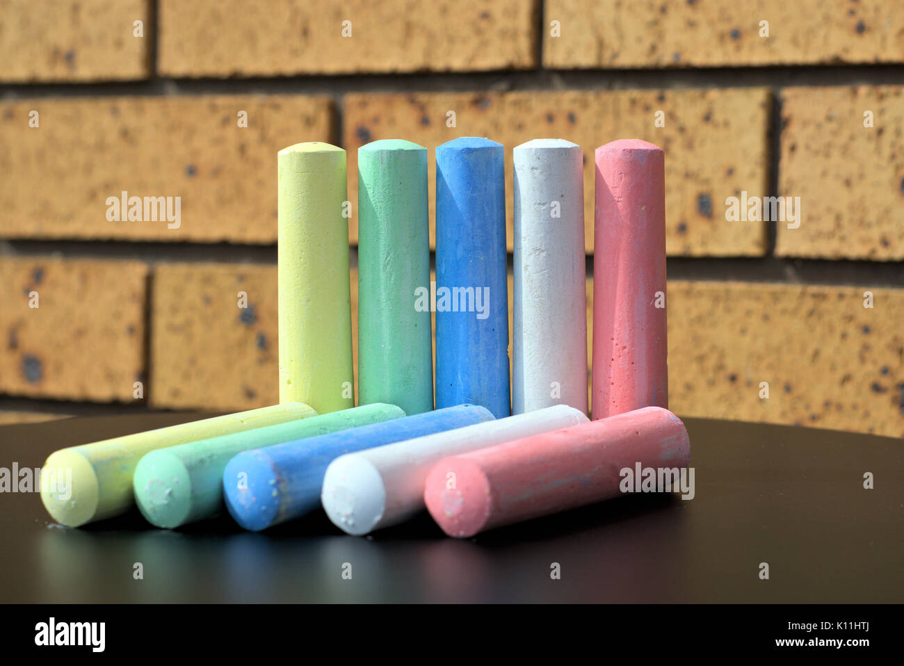 Ten chalks of five different colors on table. Concept of ten as in ten things, ten objects, ten people of different colors. Stock Photo