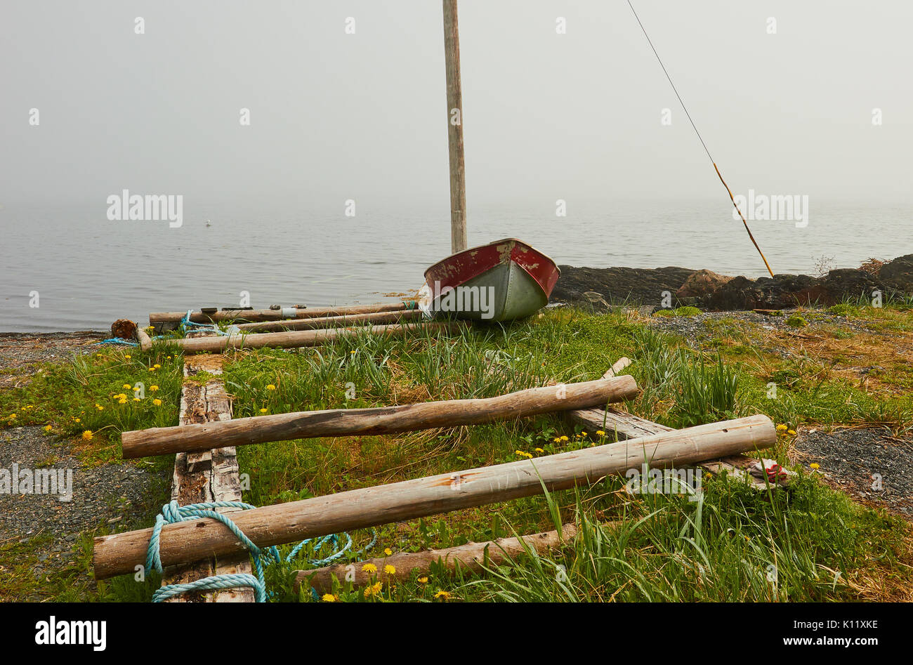 Small boat at misty water's edge and wooden boat ramp, Great Northern Peninsula, Newfoundland, Canada Stock Photo