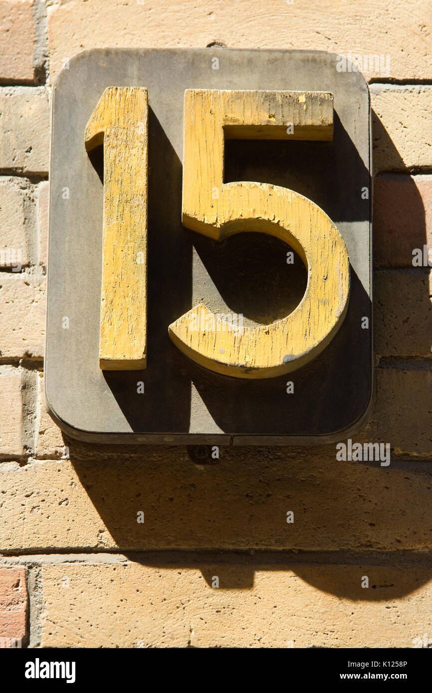 Bold number fifteen on sandstone brick wall Stock Photo
