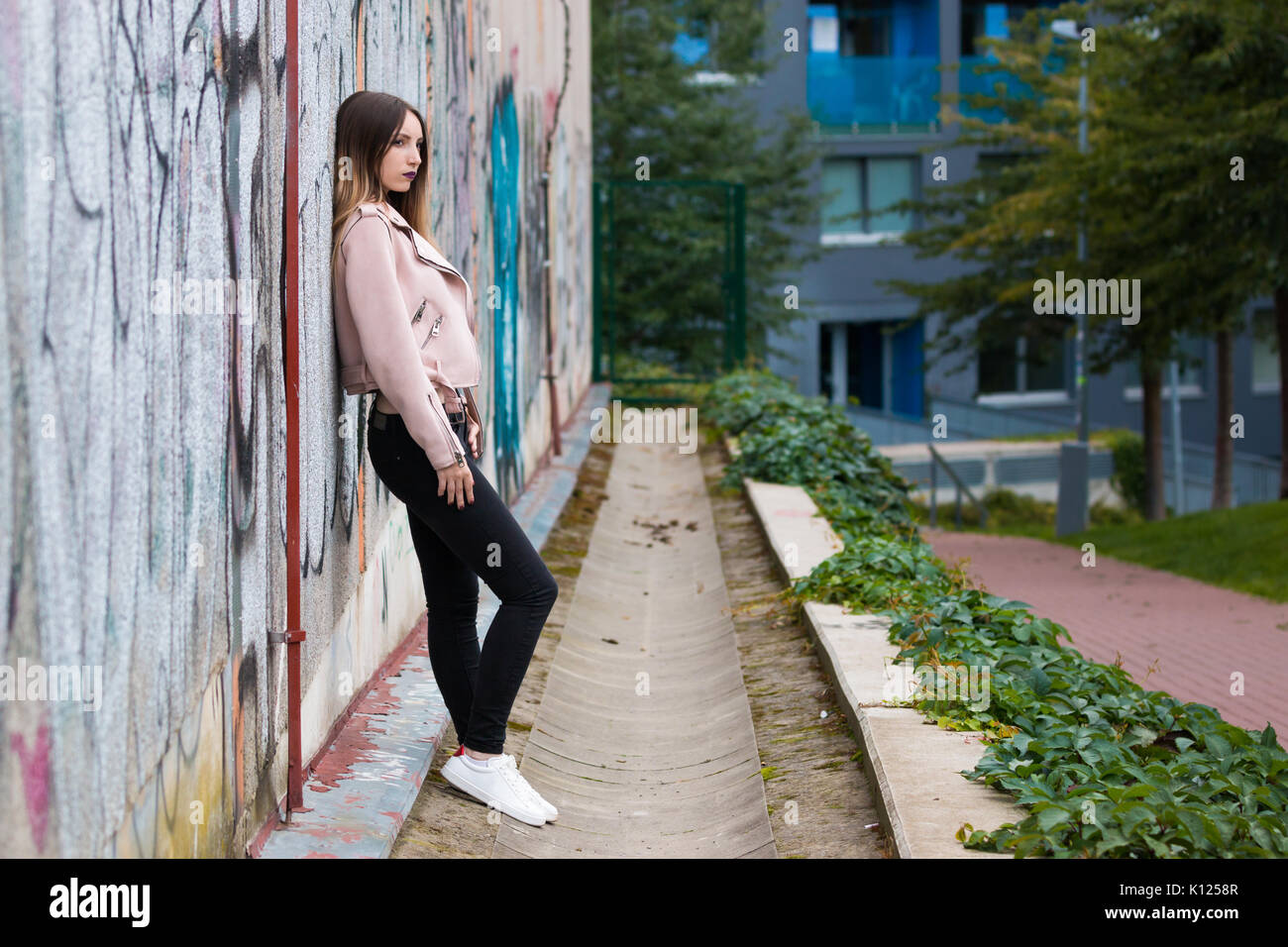 Portrait of informal fashionable girl on graffiti wall background Stock Photo