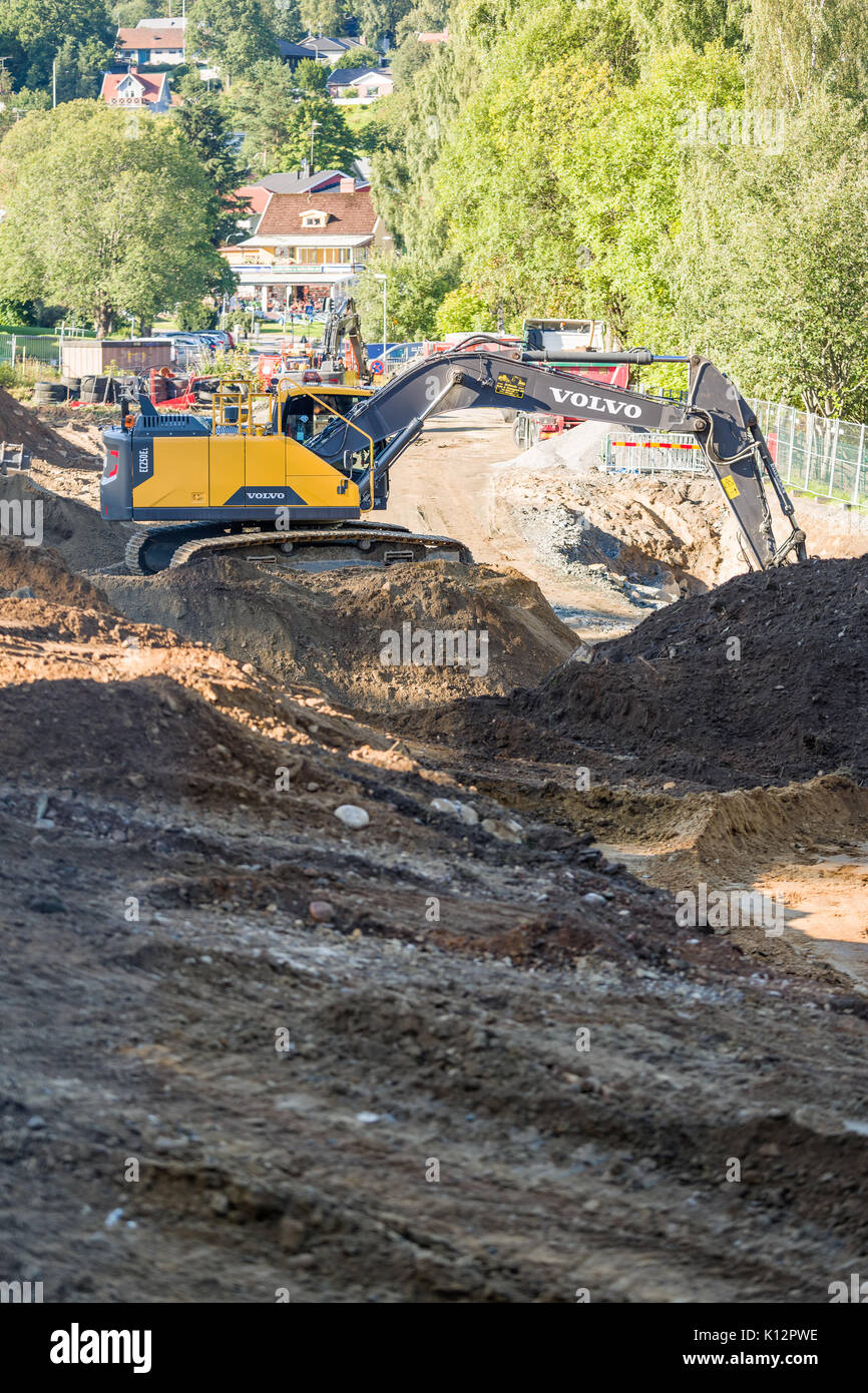 Heavy duty Volvo EC250EL excavator digging and moving piles of topsoil at building site ahead of construction  Model Release: No.  Property Release: No. Stock Photo