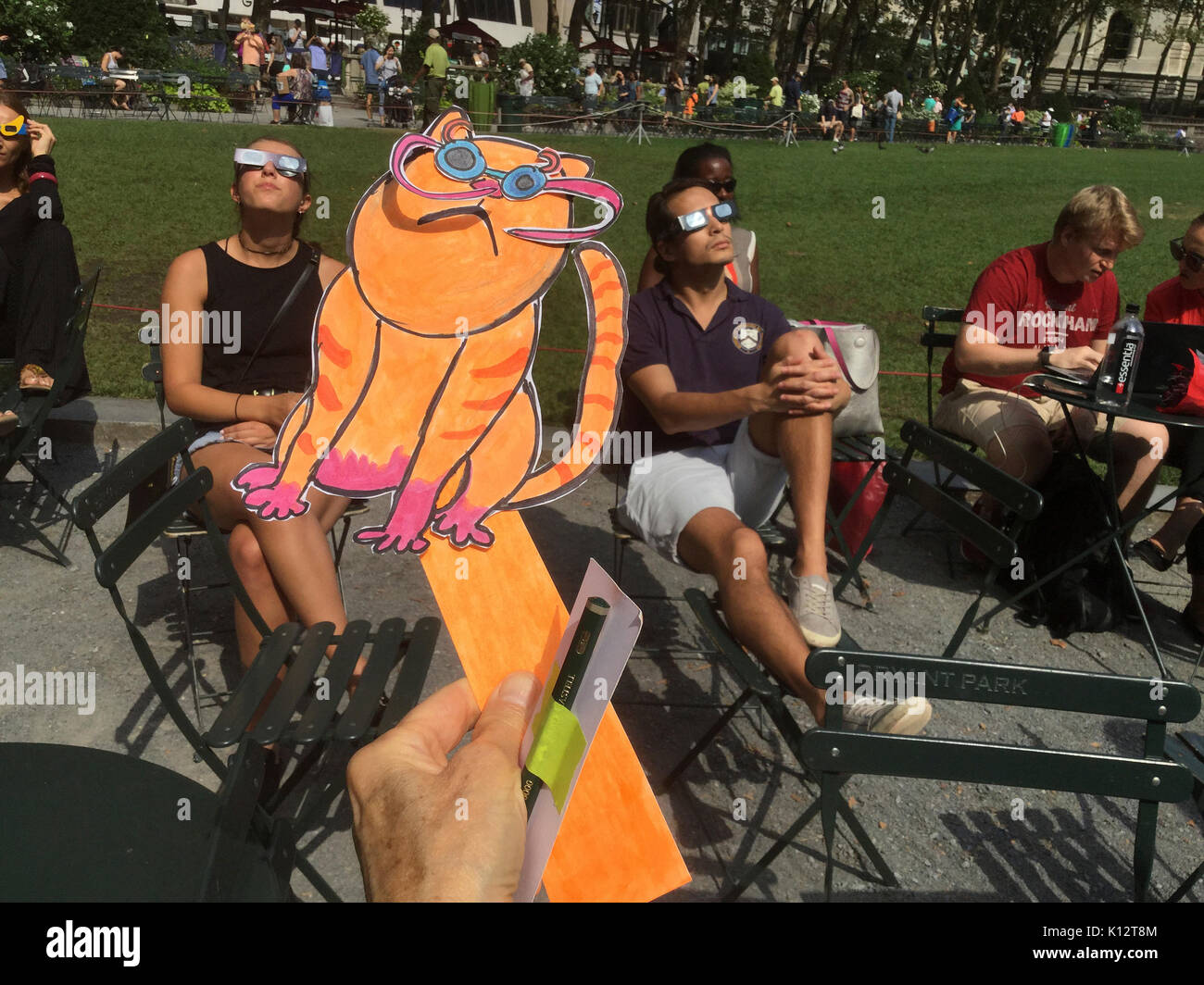 Thousands of the curious congregate in Bryant Park to watch the partial solar eclipse occurring in New York on Monday, August 21, 2017. New York City is not in the path of totality with the moon covering only almost 72 percent of the sun during the 2:44PM peak.  Eclipse Kat, drawn by Frances M. Roberts joins the crowds to watch the eclipse.  (© Frances M. Roberts) Illustration Stock Photo