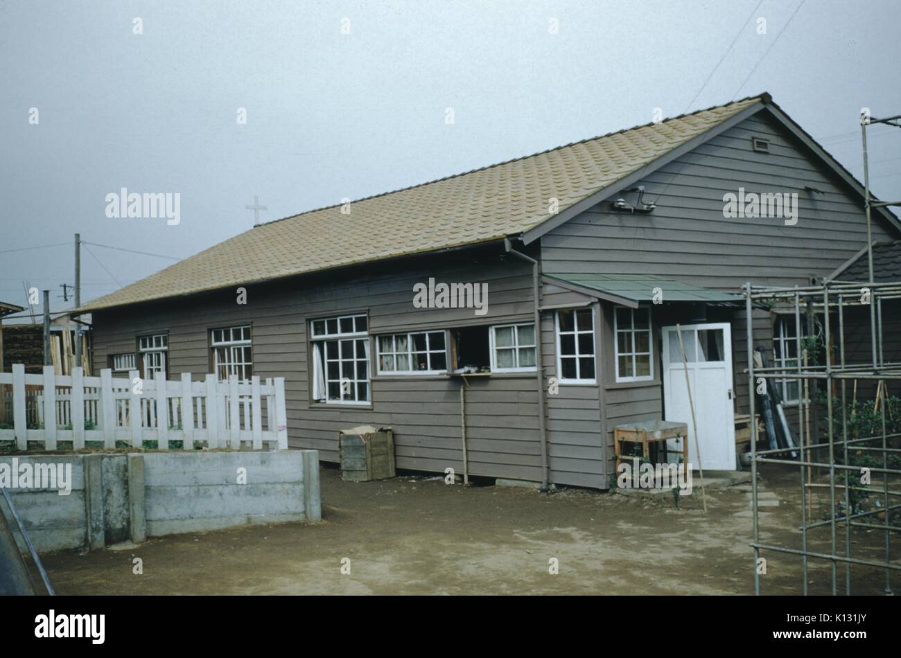 Home under construction, with metal scaffolding visible in the foreground, at the Wesleyan Methodist Mission Compound, Japan, 1952. Stock Photo
