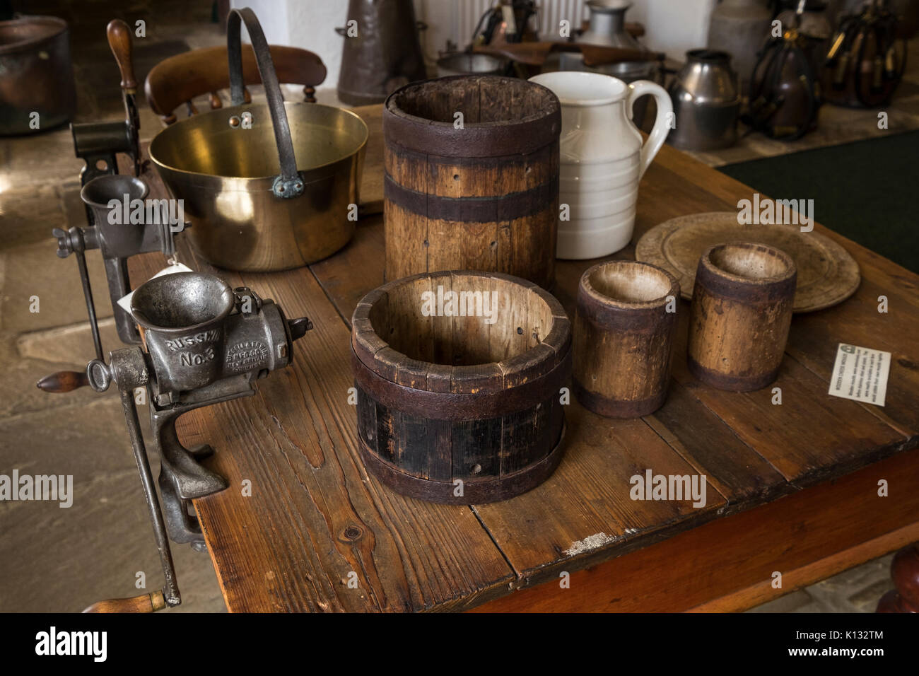 Vintage wooden cheese moulds, meat mincers, and kitchen implements on a wood table in the Hawes Creamery museum, Hawes, Yorkshire, England, UK Stock Photo