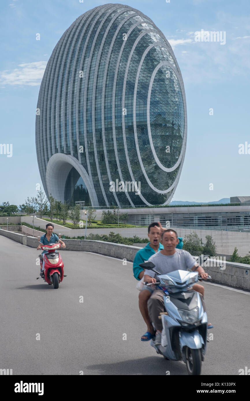 Chinese motorcyclists past Sunrise Kempinski Hotel along by the Yanqi Lake in Huairou, Beijing, China. 24-Aug-2017 Stock Photo