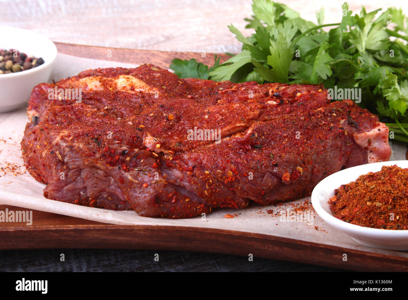 Raw beef steak with spices Leaves of coriander on wooden cutting board. Ready for cooking Stock