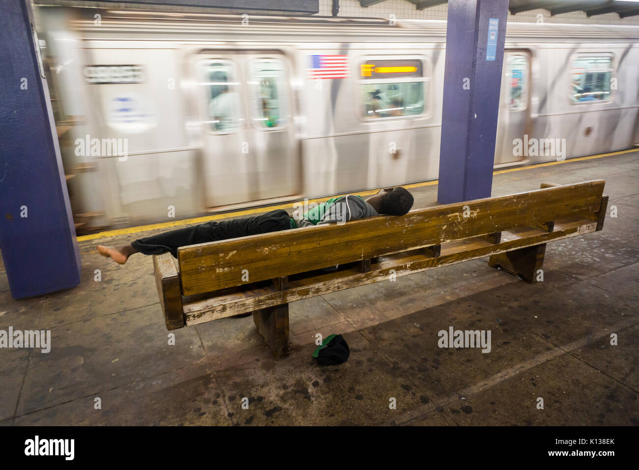 A homeless individual sleeps in a subway station in New York on Friday ...
