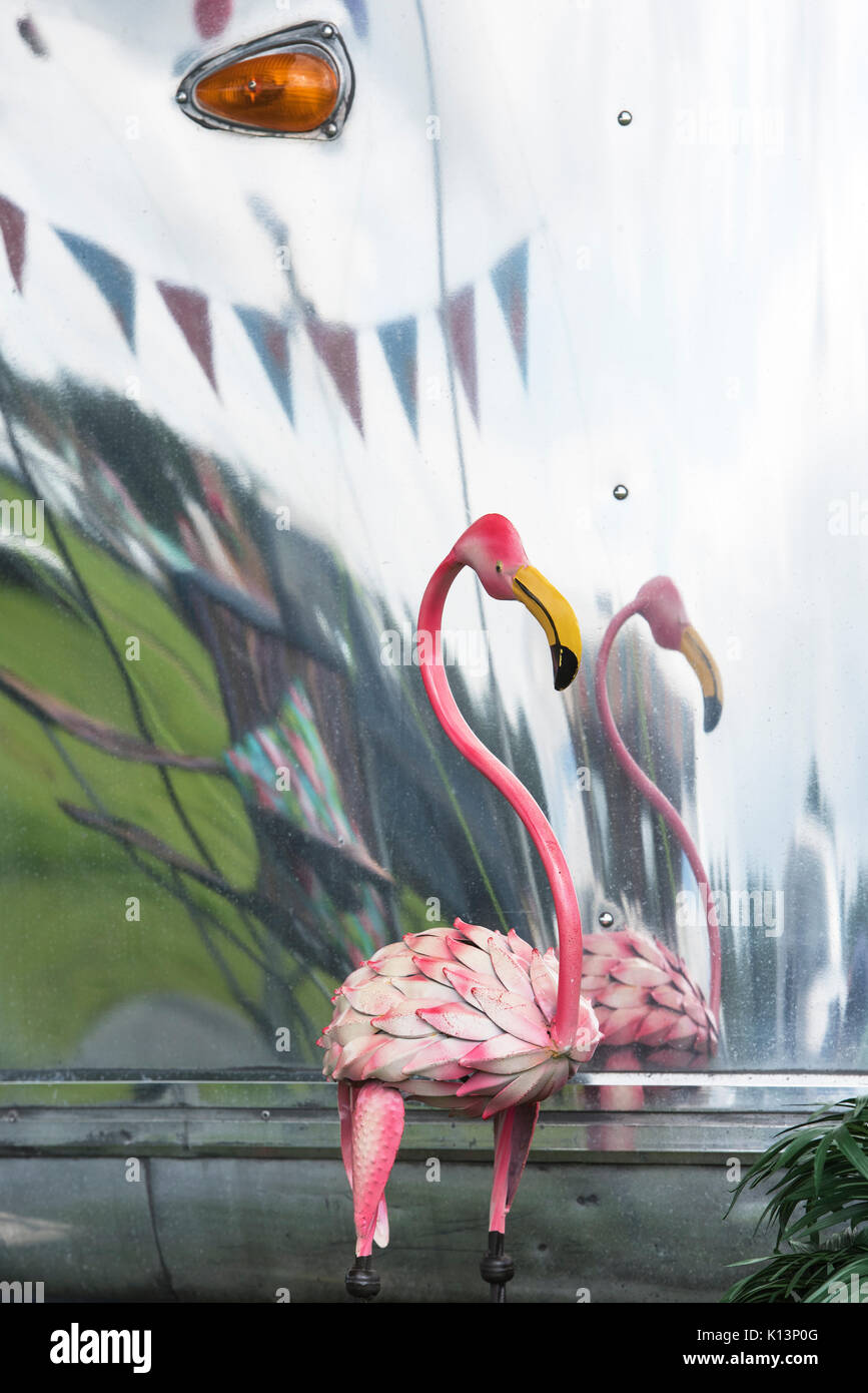 Metal pink flamingo ornament in front of an American airstream caravan at a vintage retro festival. UK Stock Photo