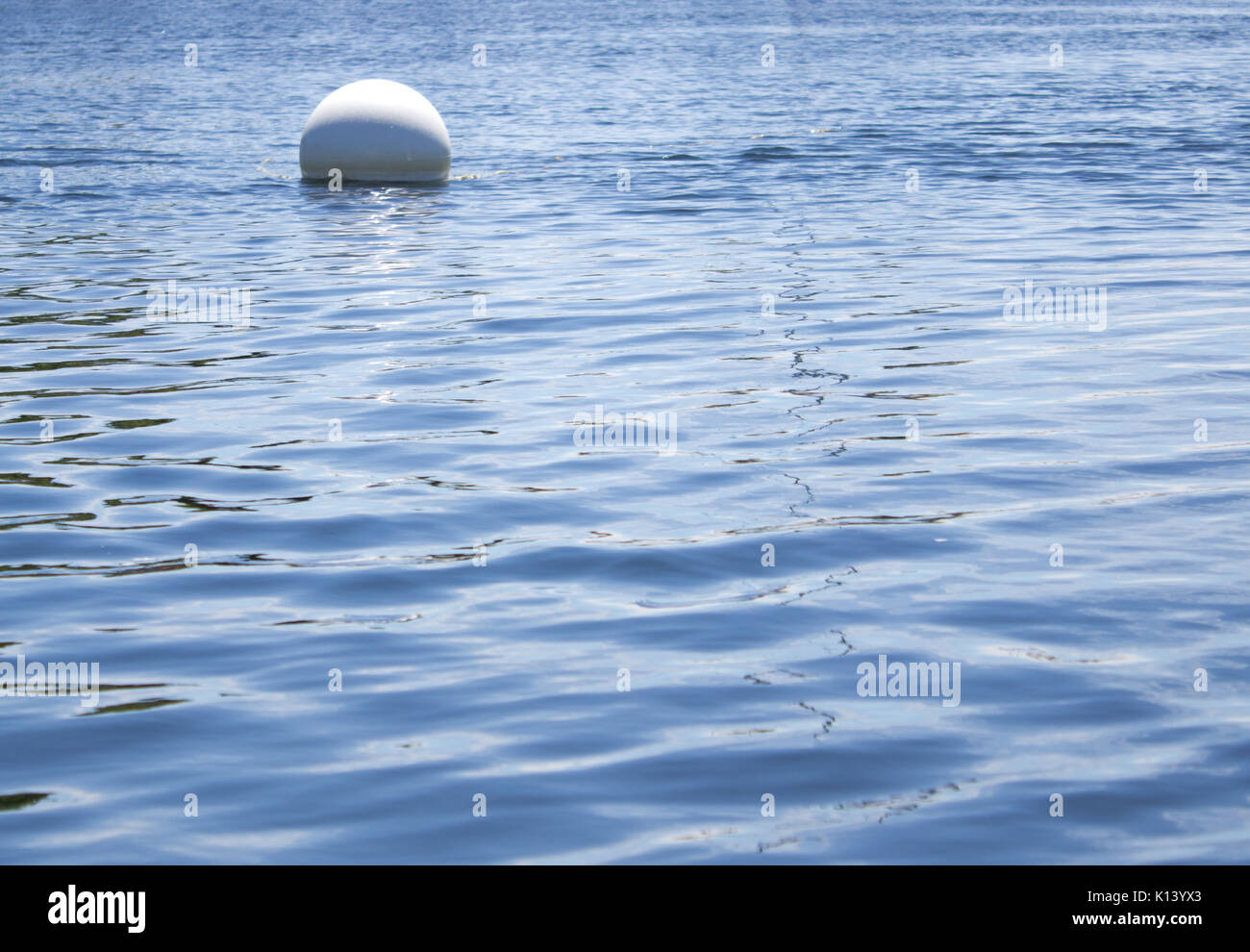 a white mooring ball or buoy floats in the blue ocean Stock Photo