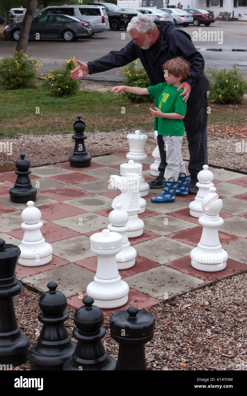 Grandfather teaching grandson how to play chess. Stock Photo