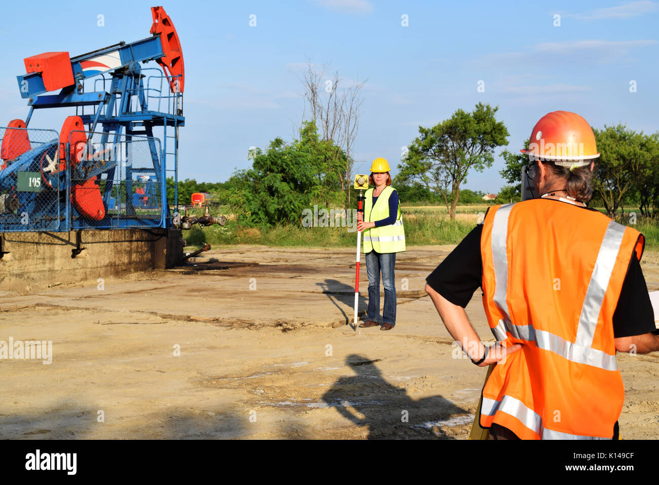 Two surveyors at work and crude oil pump in background Stock Photo Alamy