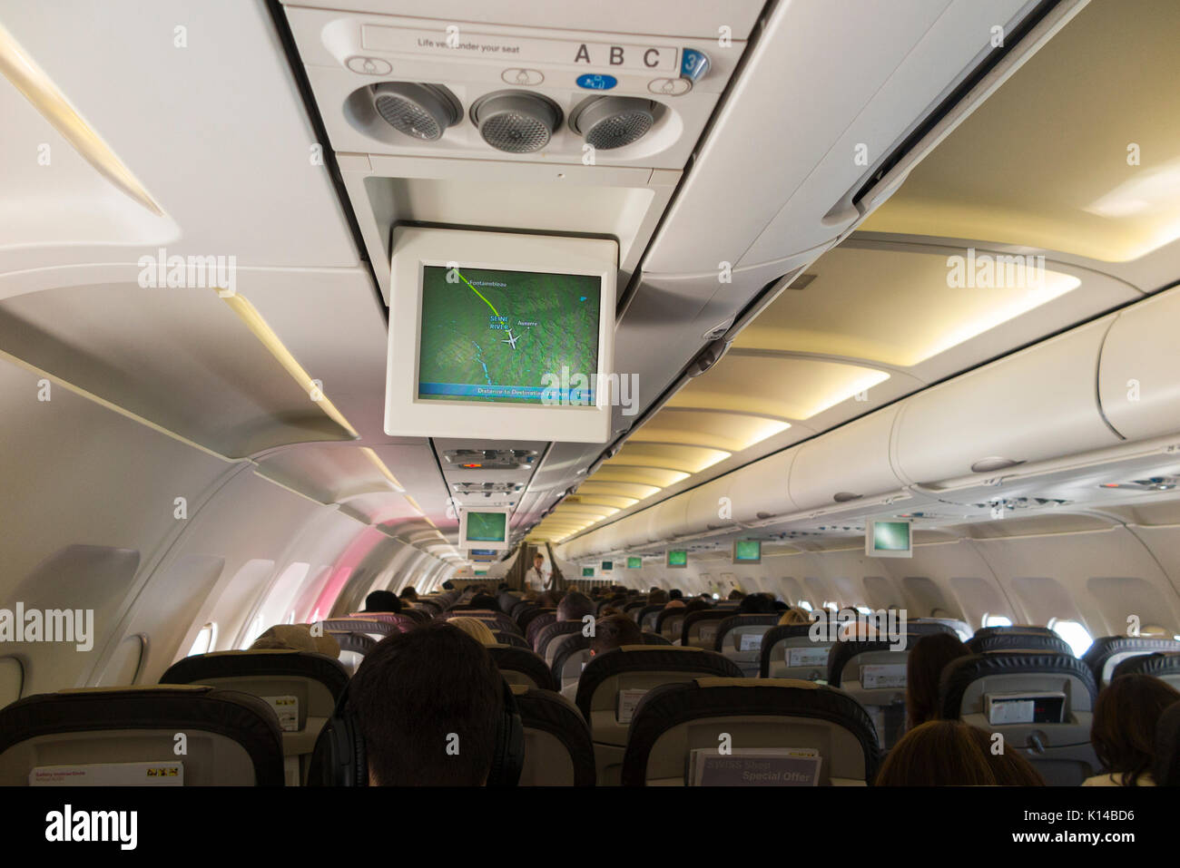 Inside an aeroplane / inside an air plane cabin with monitor flight position map display on TV screen showing aircraft postion above / over France. Stock Photo