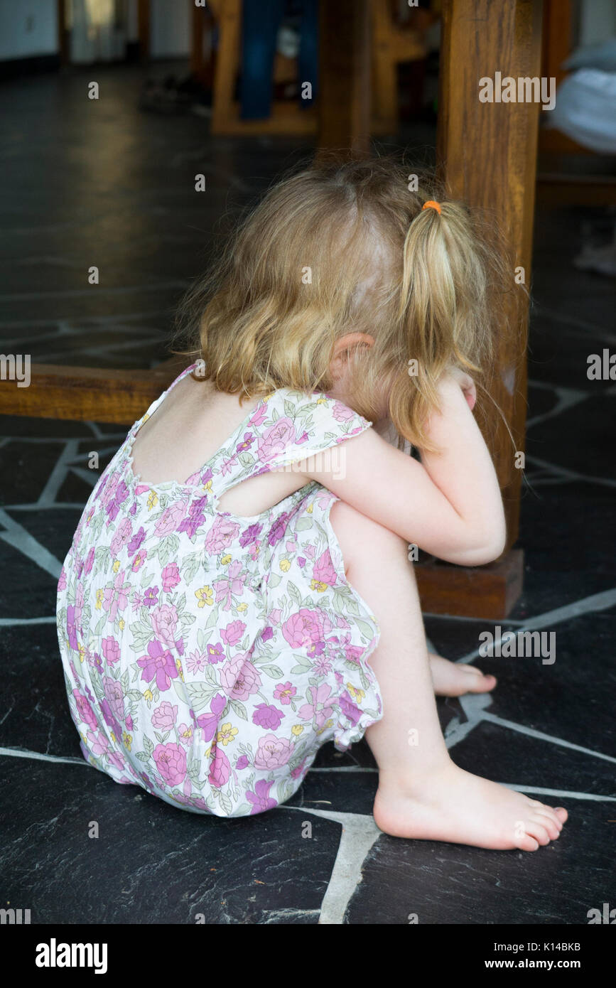 Three year old girl / kid / child on the naughty corner after being disciplined for something she has done. She is thinking about her actions. (89) Stock Photo