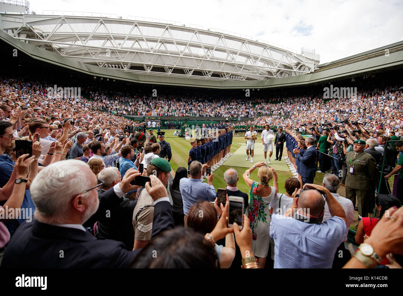 Roger Federer of Switzerland and Marin Cilic of Croatia walk off Centre Court with their trophies at the Gentlemen's Singles - Wimbledon Championships Stock Photo