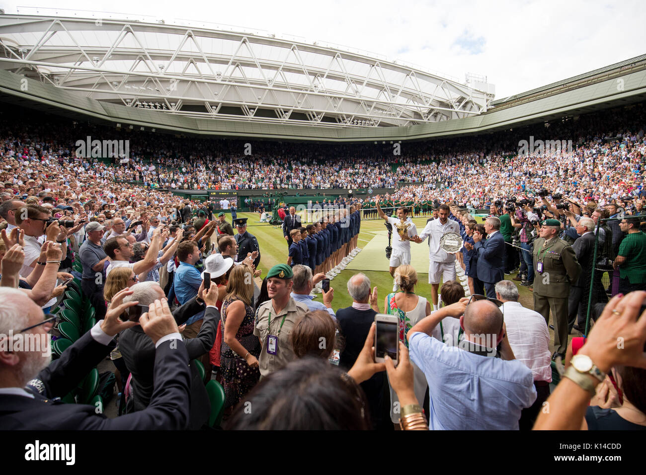 Roger Federer of Switzerland and Marin Cilic of Croatia walk off Centre Court with their trophies at the Gentlemen's Singles - Wimbledon Championships Stock Photo