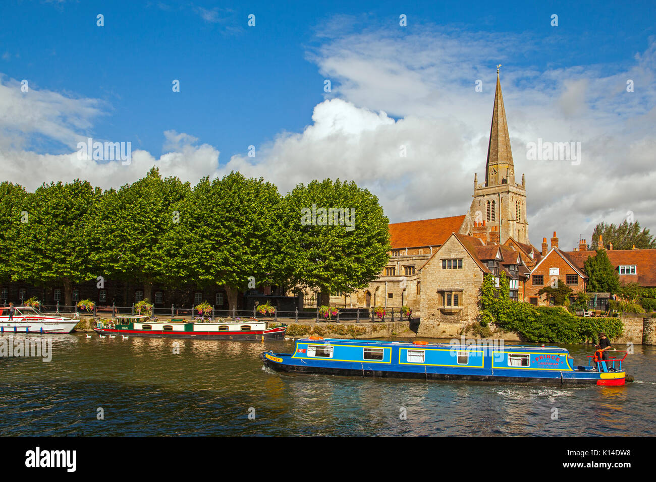 Narrow boat on the river Thames passing St Helen's church and St Helen's Wharf as seen from the Thames footpath at Abingdon on Thames Oxfordshire Stock Photo