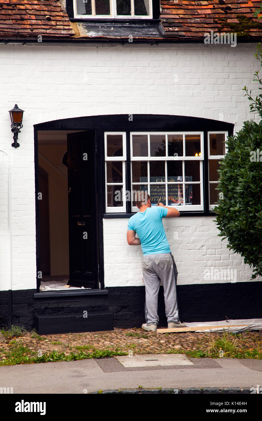 Man painting the windows of the old post office in the high street Dorchester on Thames Oxfordshire an old black and white building Stock Photo