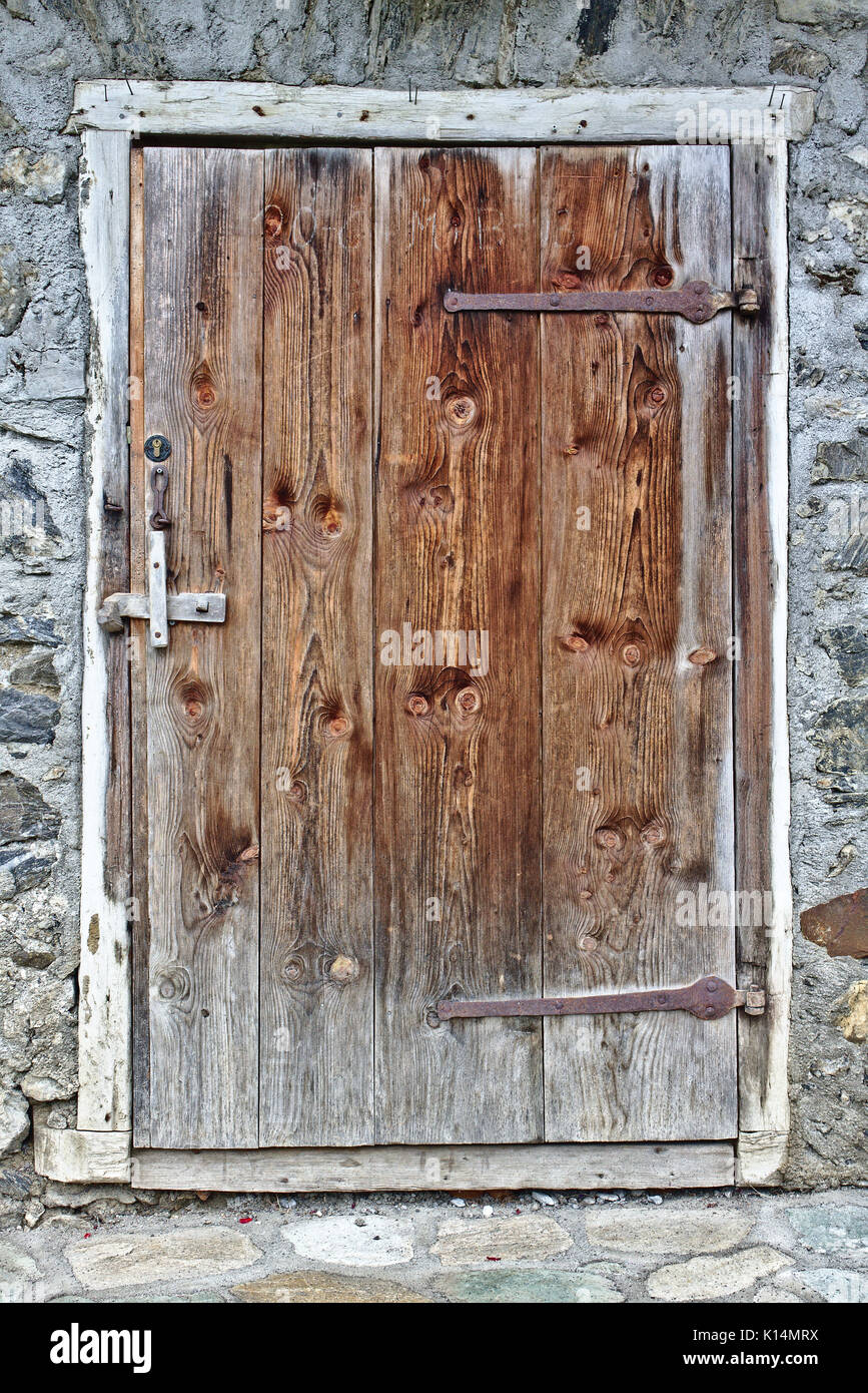 Old weathered wooden door with grey field stone wall Stock Photo