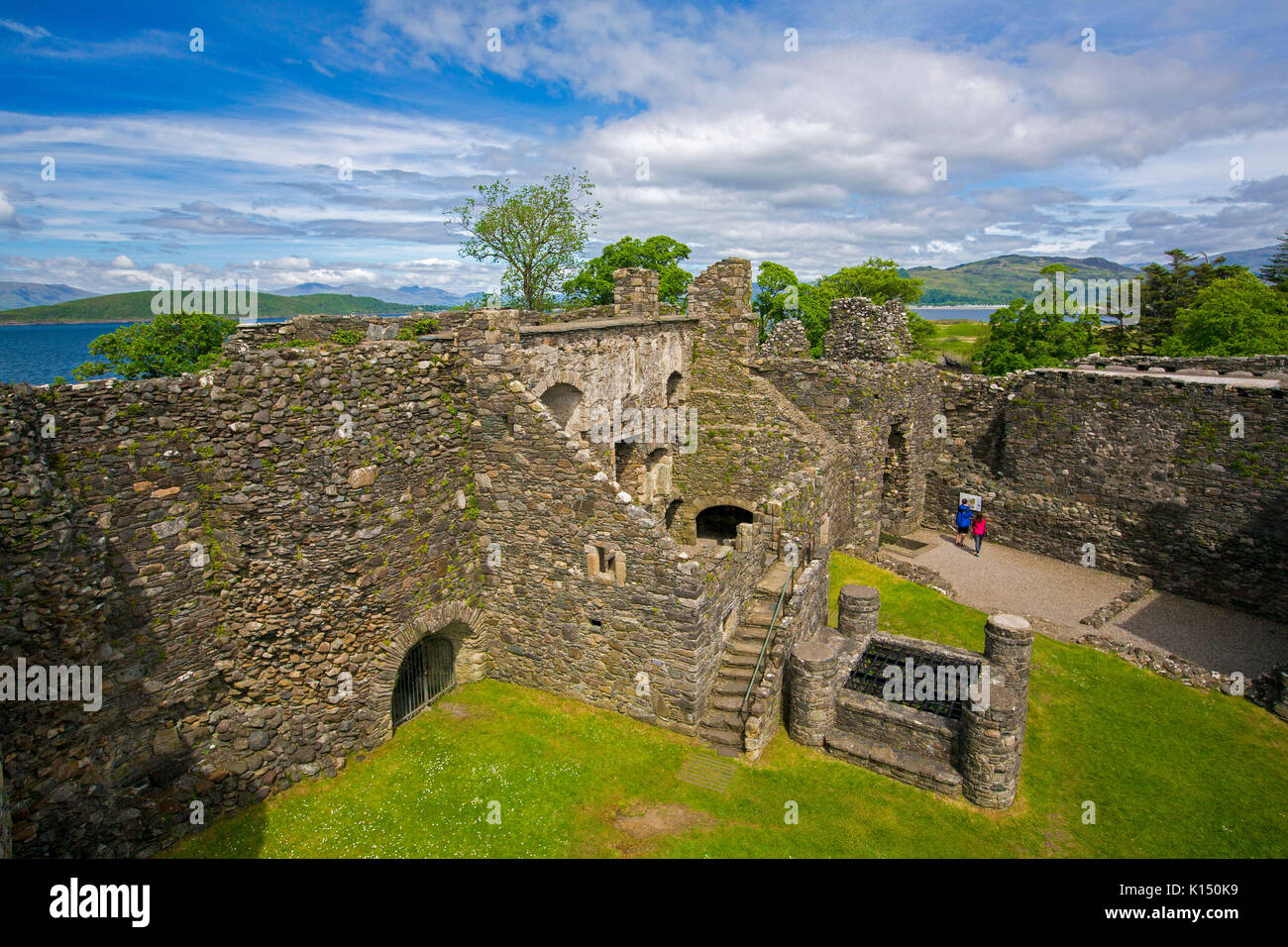 Interior of historic 13th century Dunstaffnage castle, near Oban in Scotland, under blue sky with mountains and waters of Firth of Lorn in background Stock Photo