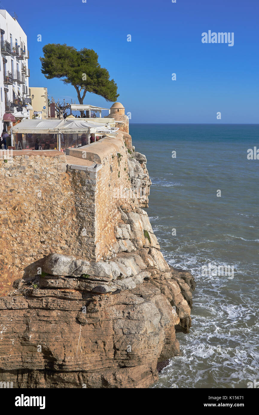 View of peñiscola cliff and mediterranean sea. In the top nany restaurants and one park with a tree Stock Photo