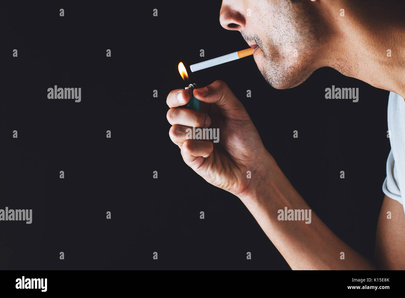 close-up of a man lighting a cigarette in a dark atmosphere Stock Photo