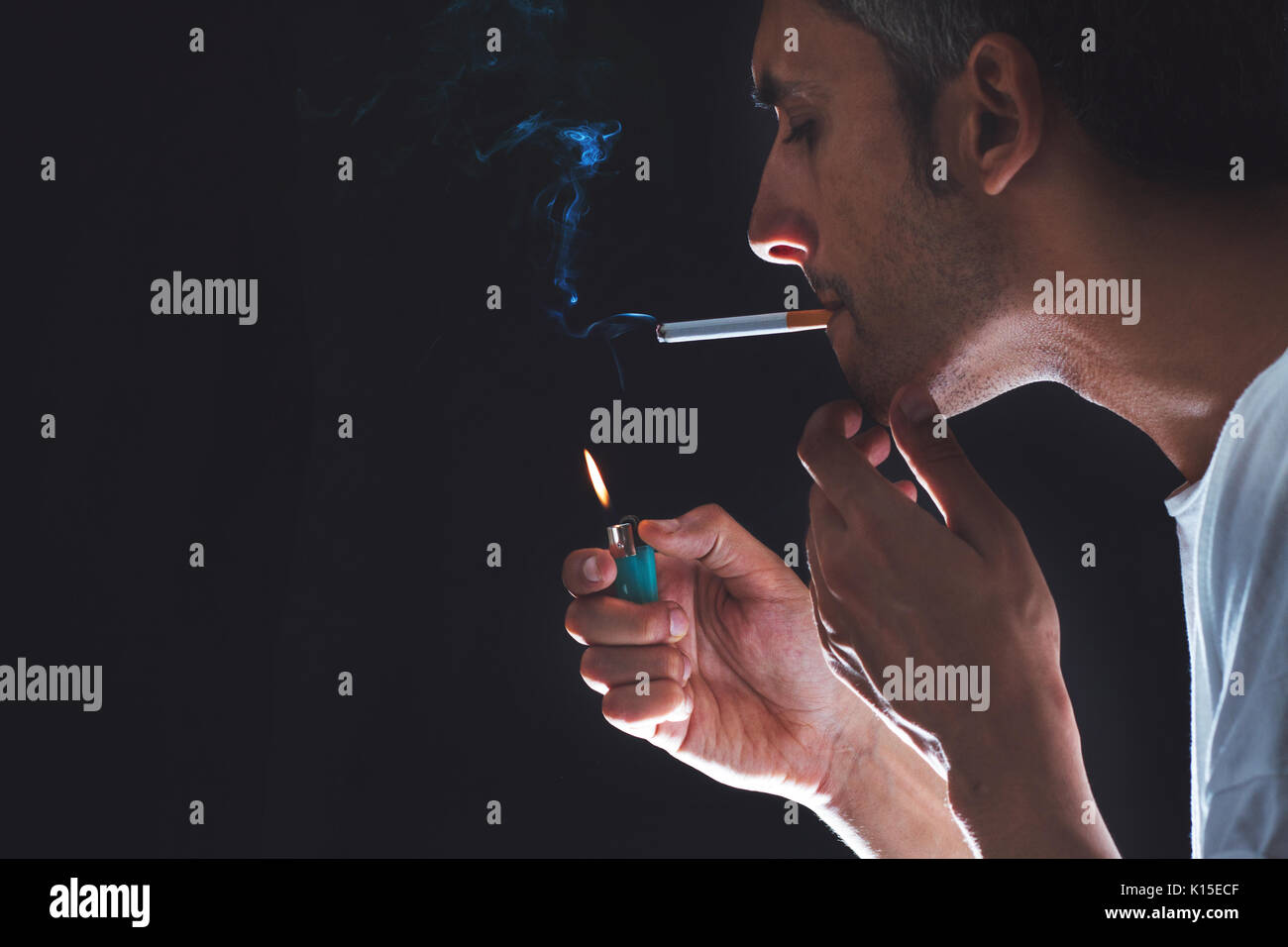 close-up of a man lighting a cigarette in a dark atmosphere Stock Photo