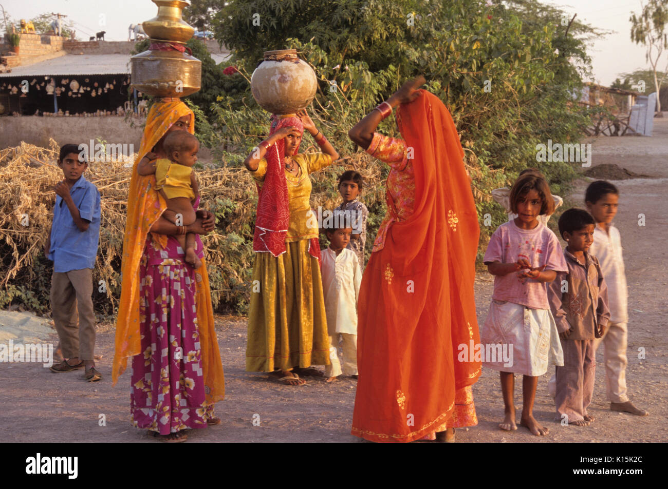 Bishnoi women (carrying pots of water on head) and children in village near Jodhpur, Rajasthan, India Stock Photo
