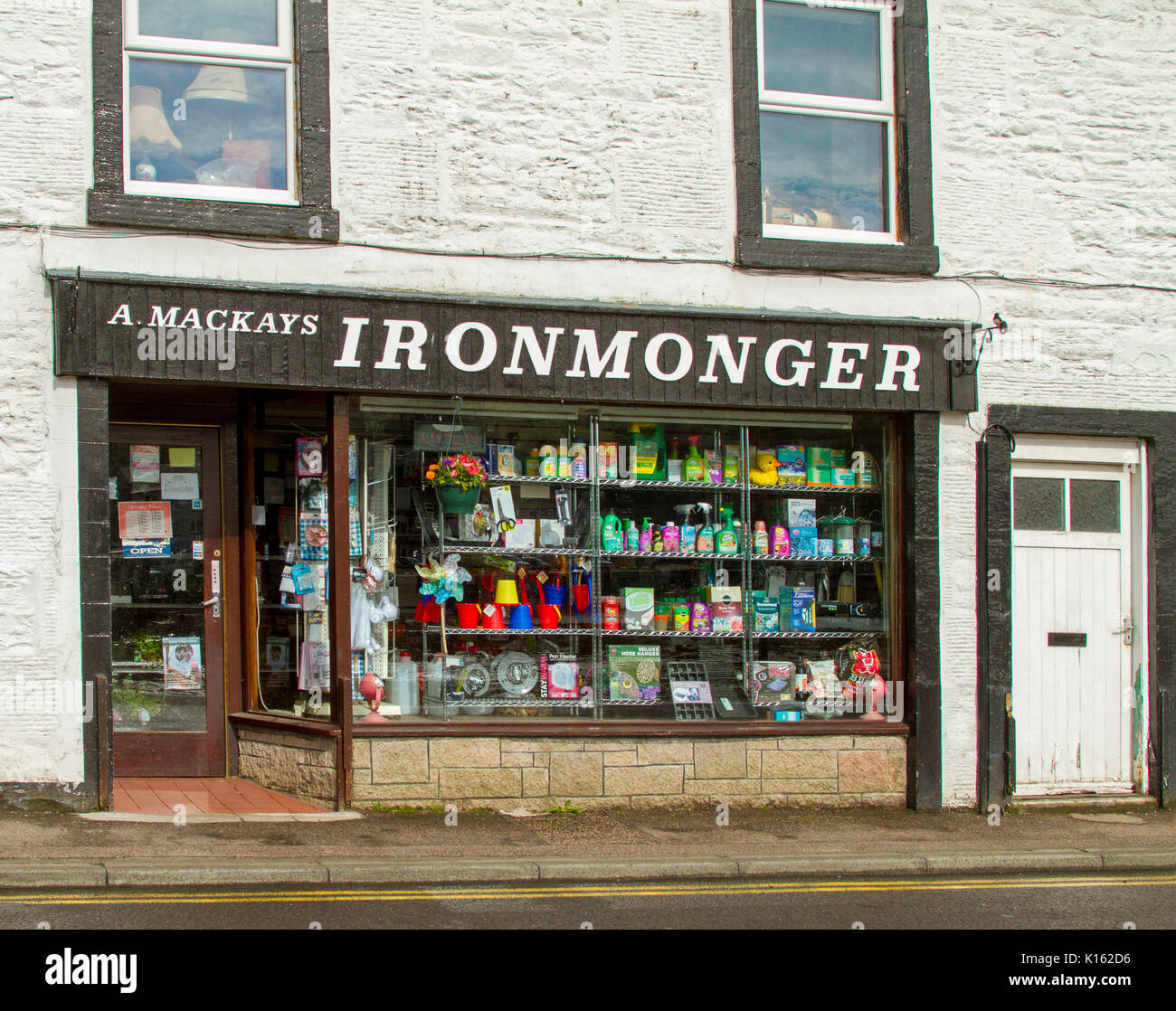 Ironmongers shop with colourful goods displayed in window of building with white-washed walls at village of Tarbert, Scotland Stock Photo