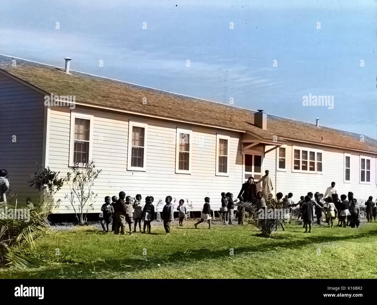 African-American children playing outside of nursery at Okeechobee migratory labor camps built by Farm Security Administration, Belle Glade, Florida, 1941. From the New York Public Library. Note: Image has been digitally colorized using a modern process. Colors may not be period-accurate. Stock Photo