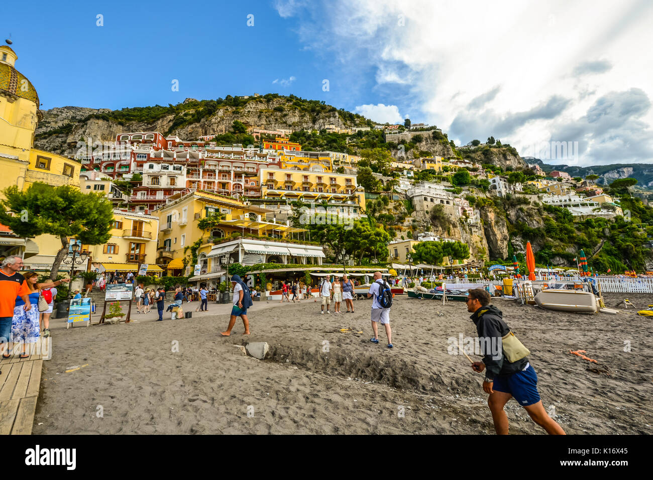 Summer day at the sandy beach of Positano Italy on the Amalfi Coast as tourists enjoy the coastal cafes and shops Stock Photo