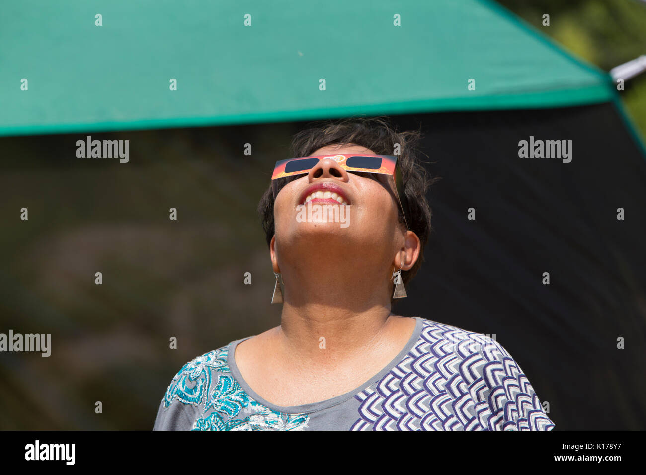 A woman wearing eclipse glasses observes the Great American Eclipse on August 21, 2017. Stock Photo