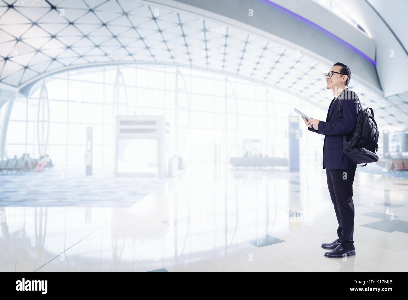 Young business man using digital pad smiling happy inside  airport waiting hall  . Stock Photo